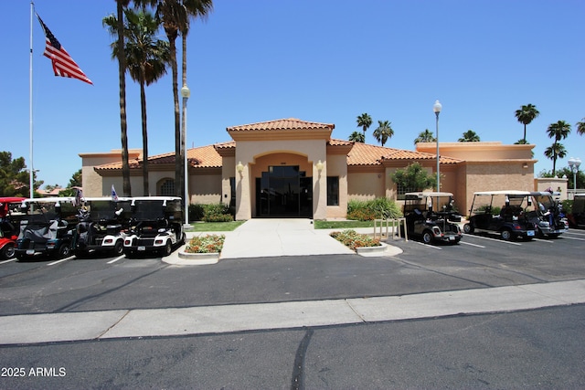view of front of property with stucco siding, uncovered parking, and a tiled roof