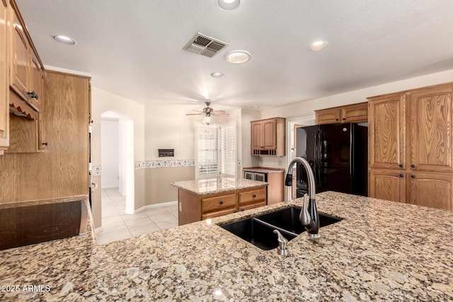 kitchen featuring black appliances, a sink, arched walkways, ceiling fan, and light tile patterned floors