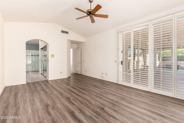 unfurnished living room with wood finished floors, ceiling fan, arched walkways, lofted ceiling, and baseboards