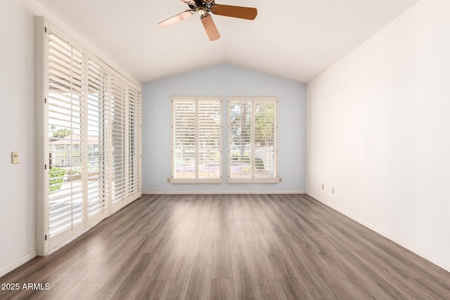 spare room with wood finished floors, ceiling fan, vaulted ceiling, and baseboards