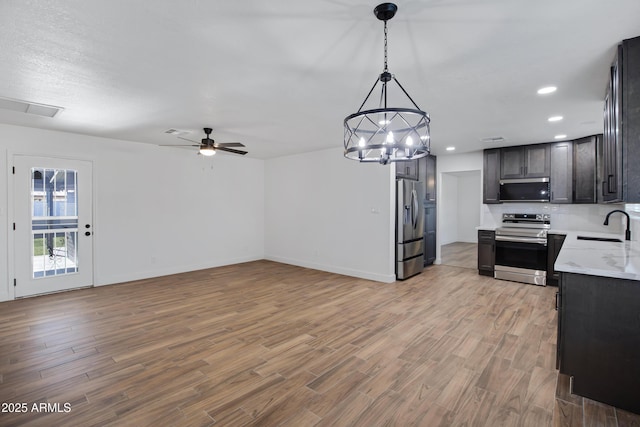 kitchen featuring dark brown cabinetry, sink, hanging light fixtures, appliances with stainless steel finishes, and light hardwood / wood-style floors