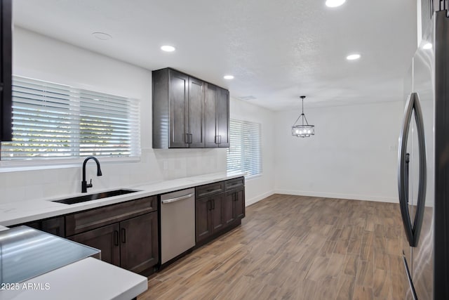 kitchen with decorative light fixtures, tasteful backsplash, sink, stainless steel appliances, and dark brown cabinets