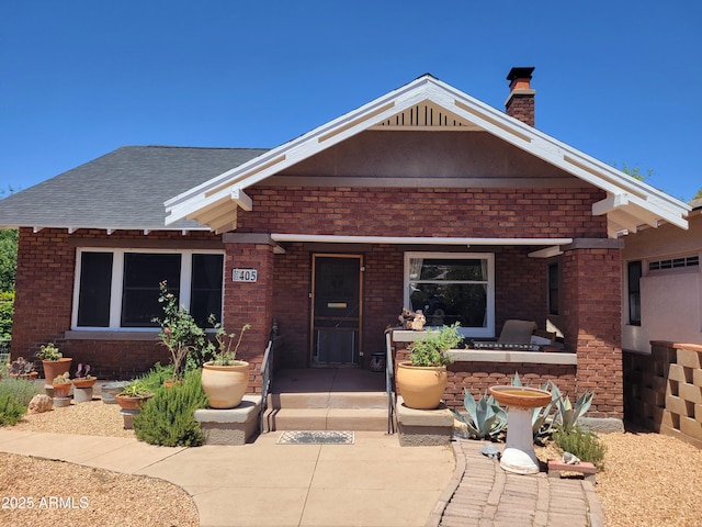 405 Powell St, Bisbee, AZ 85603 - view of front of property featuring a chimney, brick siding, roof with shingles, and a patio area