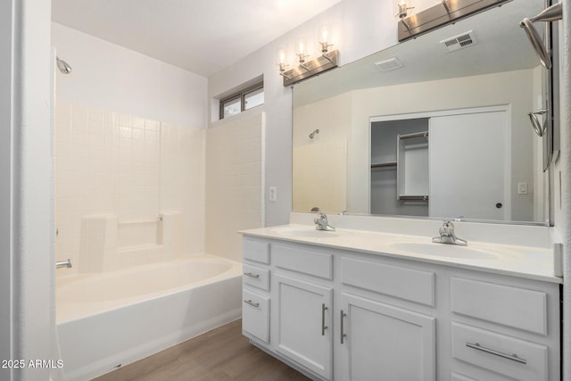 bathroom featuring double vanity, wood finished floors, visible vents, and a sink