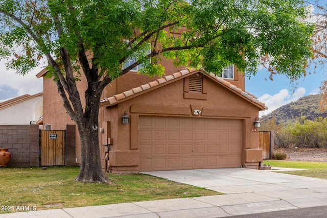 view of front facade featuring stucco siding, a tile roof, a gate, concrete driveway, and a garage