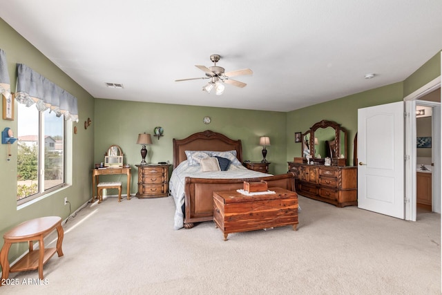 carpeted bedroom with ensuite bath and ceiling fan