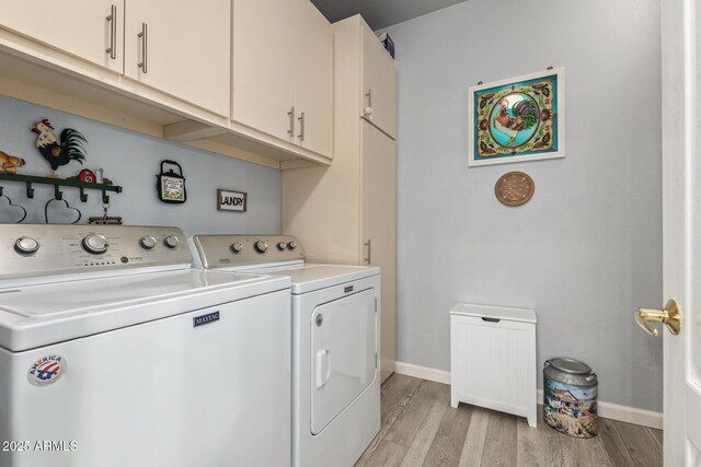 clothes washing area featuring cabinets, separate washer and dryer, and light hardwood / wood-style flooring