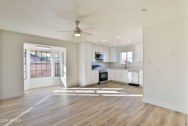 kitchen featuring light hardwood / wood-style floors, white cabinetry, a healthy amount of sunlight, and appliances with stainless steel finishes