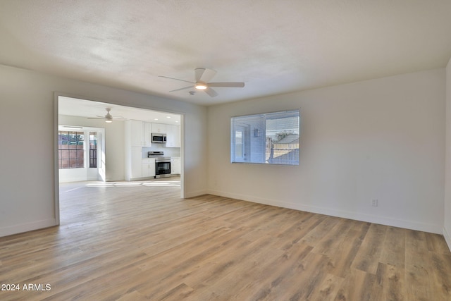 unfurnished living room featuring ceiling fan, light hardwood / wood-style flooring, and a textured ceiling