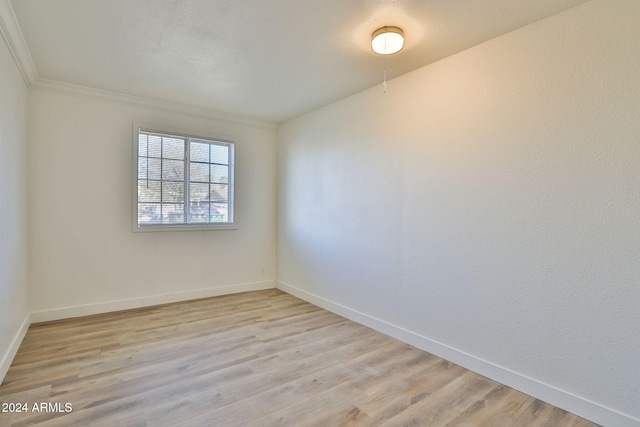 empty room featuring crown molding and light hardwood / wood-style floors