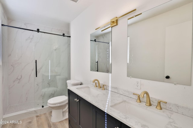 bathroom with tiled shower, hardwood / wood-style floors, vanity, and toilet