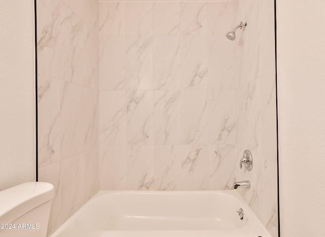 bathroom with tiled shower / bath combo and toilet