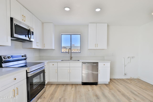 kitchen with white cabinets, light hardwood / wood-style floors, sink, and appliances with stainless steel finishes