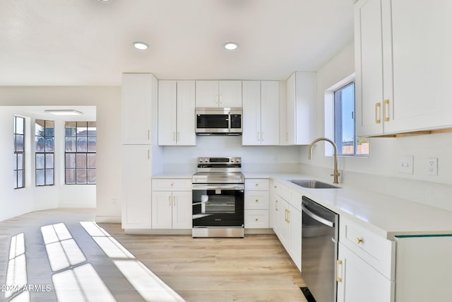 kitchen featuring white cabinetry, sink, light hardwood / wood-style flooring, and appliances with stainless steel finishes