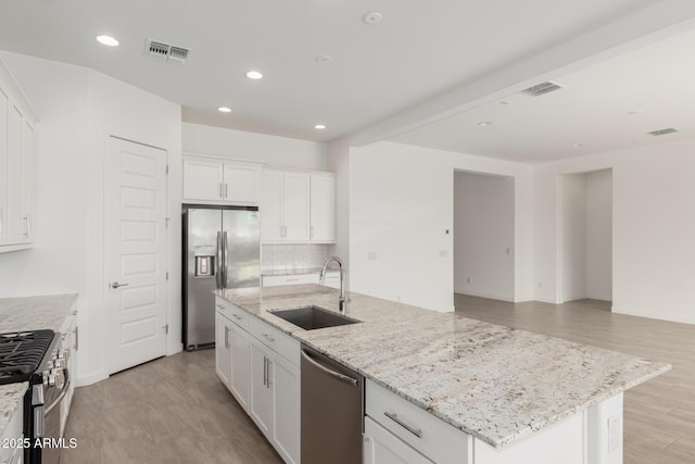 19151 W Coolidge St, Litchfield Park, AZ 85340 - kitchen featuring stainless steel appliances, a sink, a center island with sink, white cabinetry, and light wood-style floors