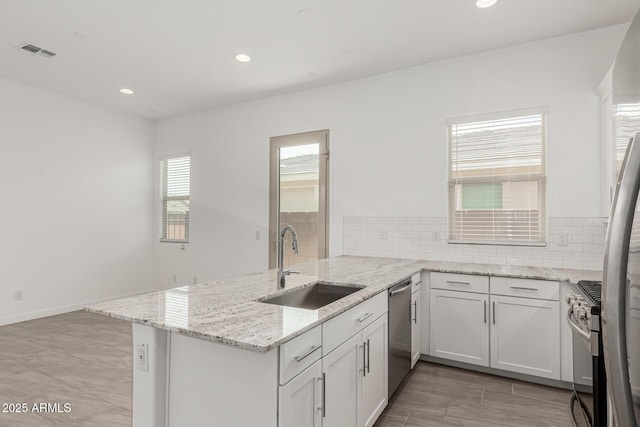 19151 W Coolidge St, Litchfield Park, AZ 85340 - kitchen featuring a sink, stainless steel appliances, a peninsula, light stone countertops, and backsplash