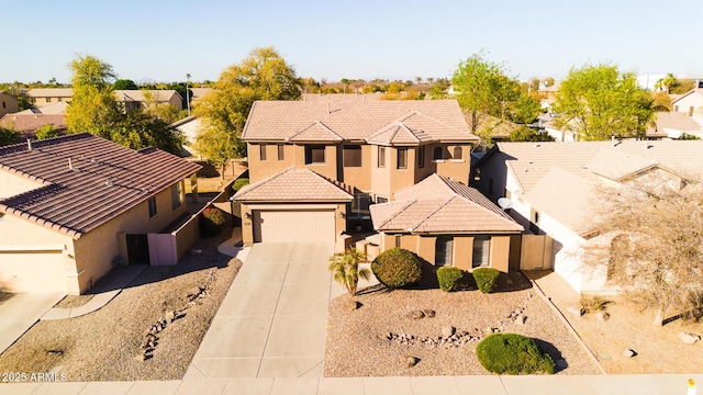 view of front facade featuring a tile roof, stucco siding, a garage, a residential view, and driveway