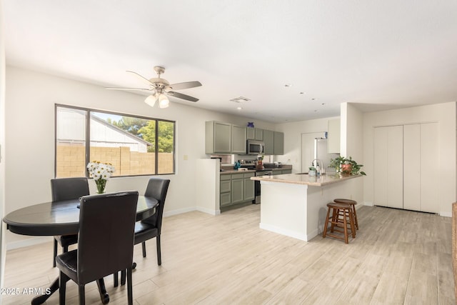 kitchen with sink, light stone counters, ceiling fan, light hardwood / wood-style floors, and appliances with stainless steel finishes