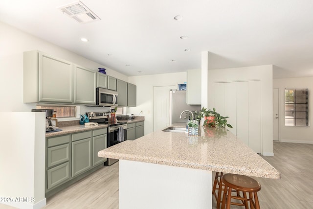 kitchen with kitchen peninsula, light stone countertops, stainless steel appliances, a kitchen breakfast bar, and sink