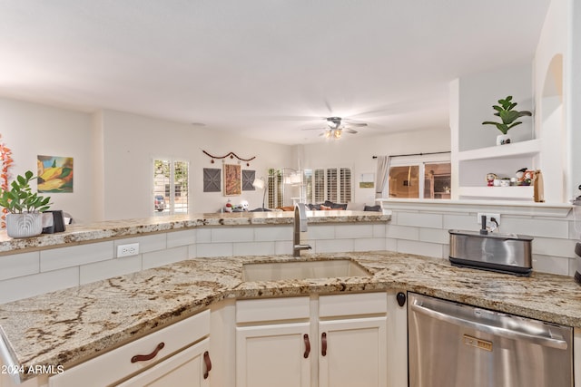 kitchen featuring light stone counters, sink, stainless steel dishwasher, and white cabinets