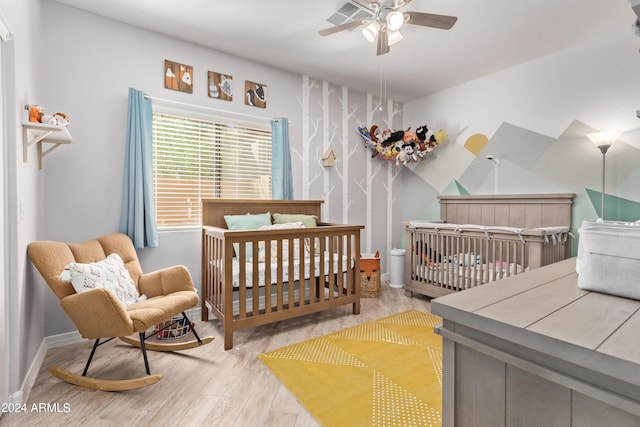 bedroom featuring ceiling fan, light hardwood / wood-style floors, and a nursery area