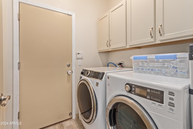 washroom with cabinets, light wood-type flooring, and washing machine and clothes dryer