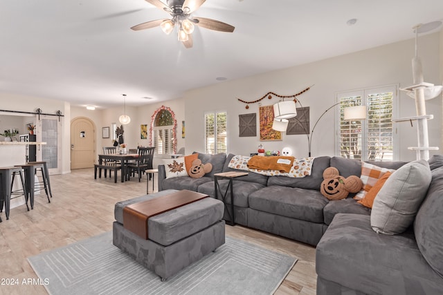 living room with a barn door, light hardwood / wood-style flooring, and ceiling fan