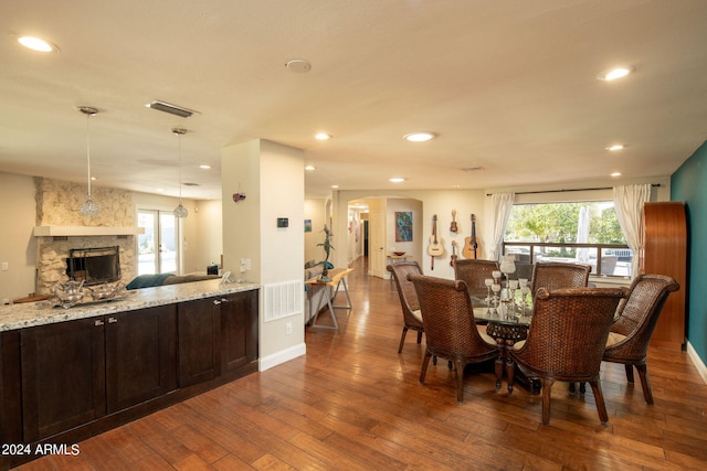 dining room with dark wood-type flooring and a stone fireplace