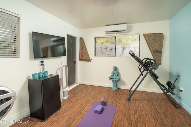 exercise room with an AC wall unit and dark hardwood / wood-style flooring