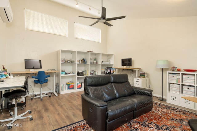 office space featuring a high ceiling, hardwood / wood-style floors, ceiling fan, and a wall unit AC