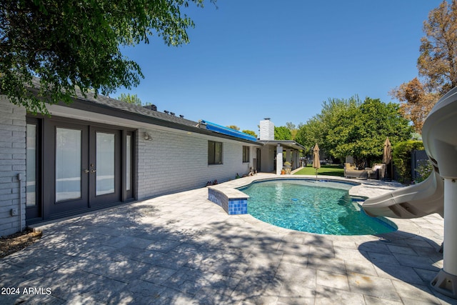 view of swimming pool with a water slide, french doors, and a patio area