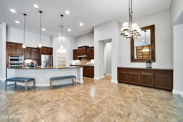 kitchen with dark stone countertops, stainless steel appliances, an inviting chandelier, and decorative light fixtures