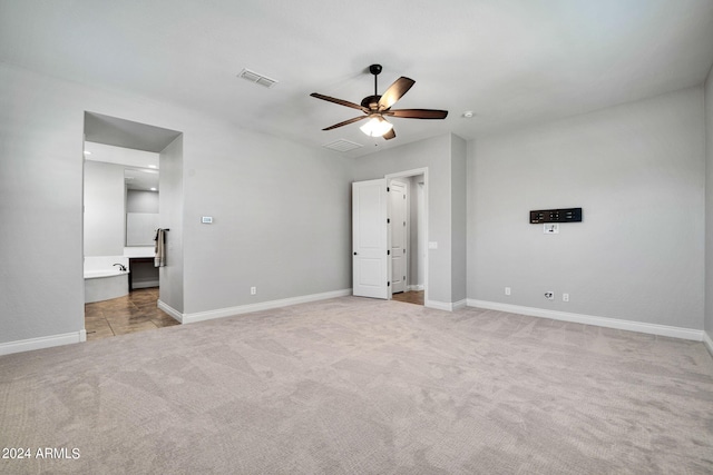 unfurnished bedroom featuring ceiling fan, light carpet, and ensuite bath