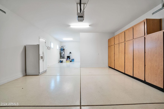 garage featuring strapped water heater, stainless steel fridge, and a garage door opener