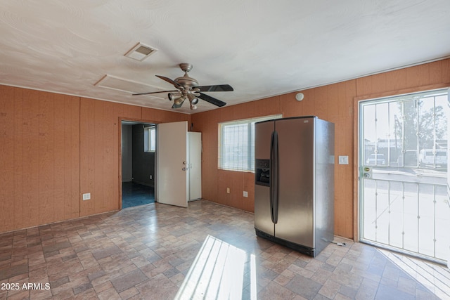 kitchen with wood walls, ceiling fan, and stainless steel fridge