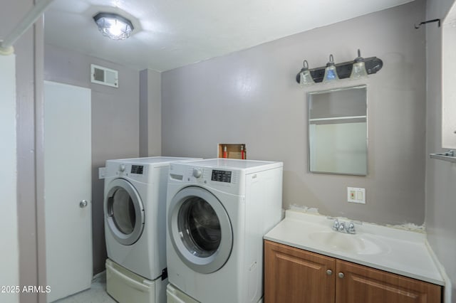 clothes washing area featuring independent washer and dryer, cabinets, and sink