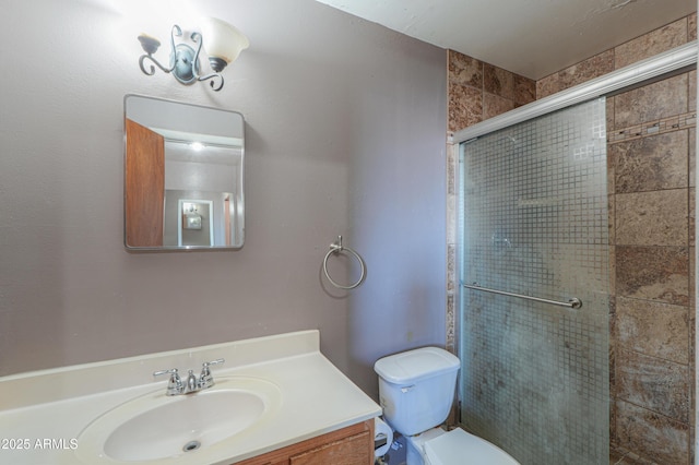 bathroom featuring toilet, a shower with shower door, and vanity