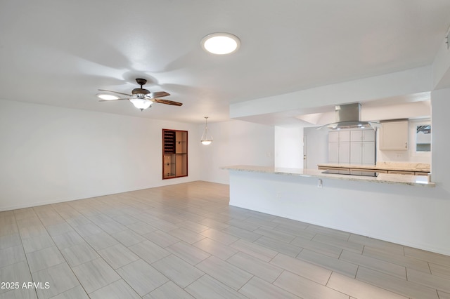 unfurnished living room with a ceiling fan and baseboards