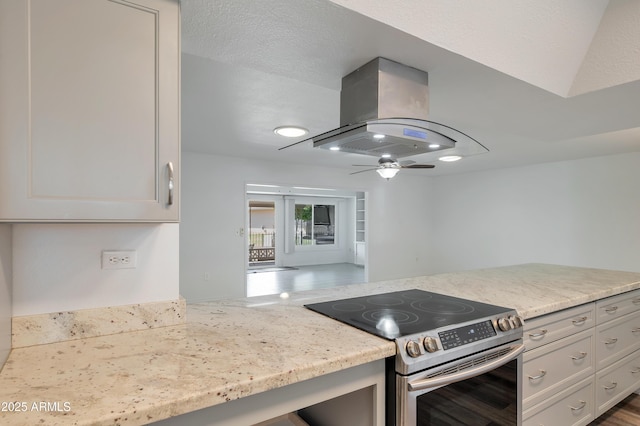 kitchen with island exhaust hood, open floor plan, ceiling fan, light stone countertops, and stainless steel electric range