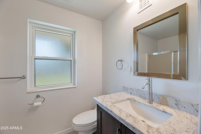 bathroom featuring a shower with shower door, vanity, and toilet