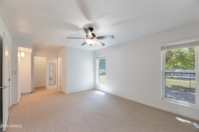 unfurnished room with baseboards, ceiling fan, and light colored carpet