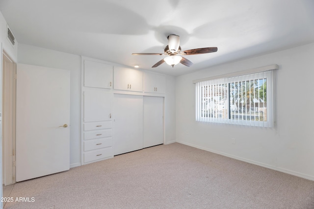 unfurnished bedroom with baseboards, visible vents, a closet, and light colored carpet