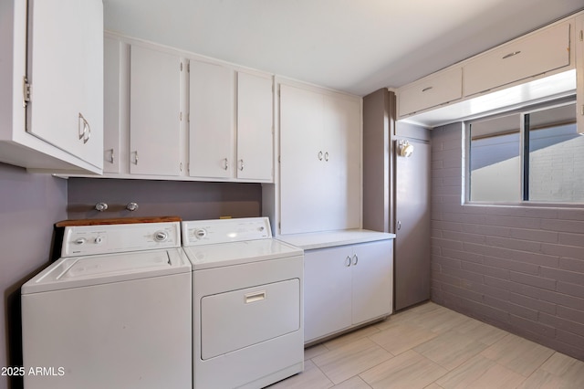 clothes washing area featuring cabinet space and washer and clothes dryer