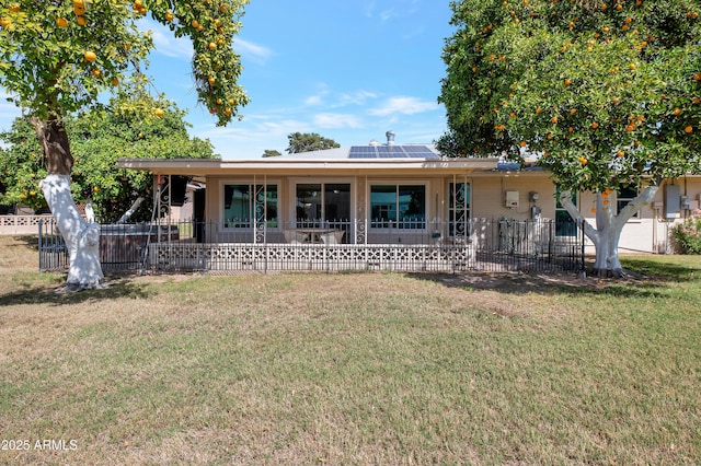 ranch-style house with a front yard, fence, and roof mounted solar panels