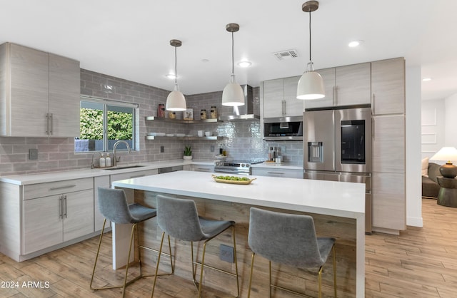 kitchen with wall chimney exhaust hood, light hardwood / wood-style floors, sink, stainless steel appliances, and backsplash