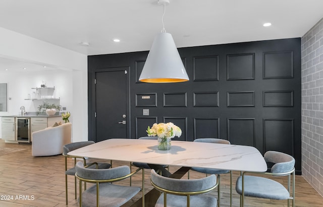 dining area with beverage cooler, light hardwood / wood-style flooring, and sink