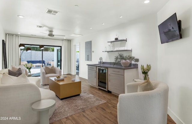 living room with ceiling fan, wine cooler, wet bar, and dark hardwood / wood-style floors