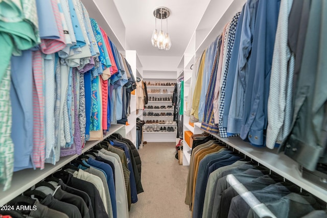 walk in closet featuring a chandelier and carpet flooring