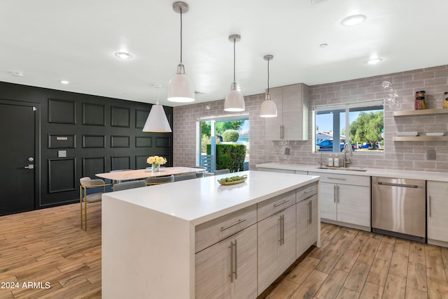 kitchen featuring pendant lighting, a kitchen island, stainless steel dishwasher, light hardwood / wood-style flooring, and plenty of natural light