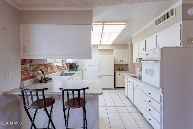 kitchen with a kitchen bar, sink, white cabinetry, kitchen peninsula, and white appliances